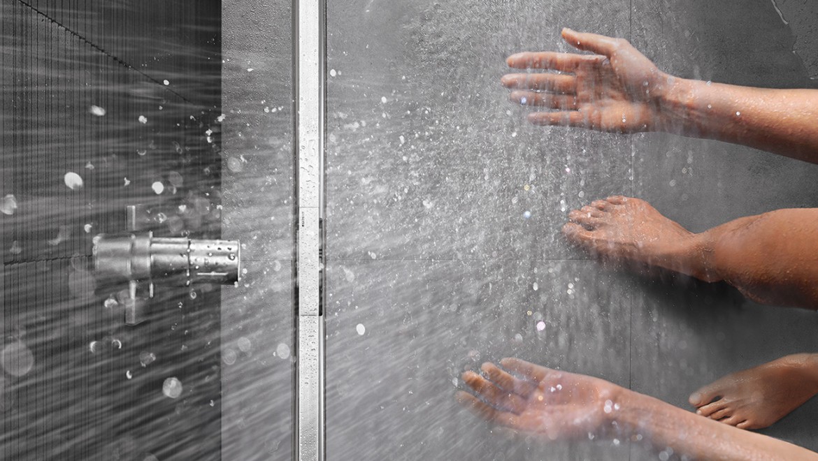 Persona che si fa la doccia in una doccia a filo pavimento con canaletta doccia Geberit CleanLine