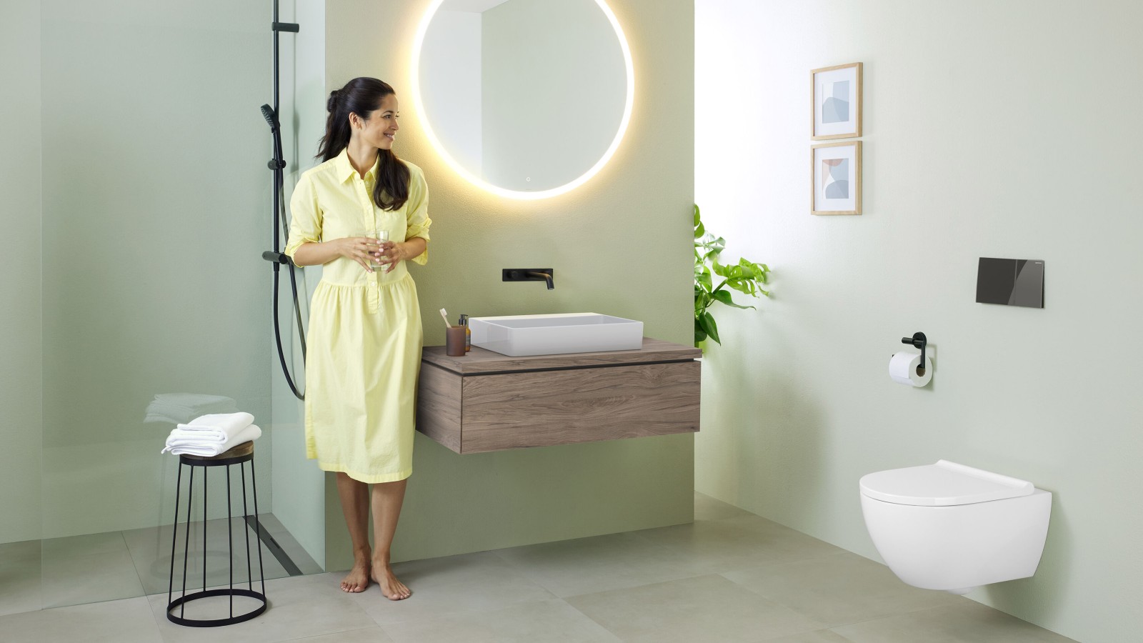 Donna in bagno con specchio Geberit Option e lavabo Geberit VariForm Donna in bagno con specchio Geberit Option e lavabo Geberit VariForm