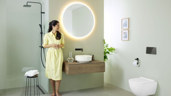Donna in bagno con specchio Geberit Option e lavabo Geberit VariForm