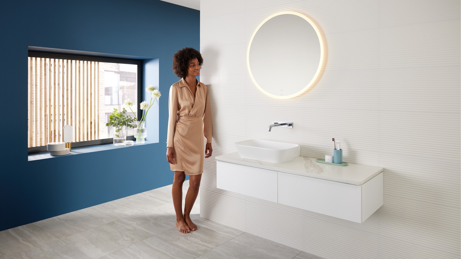 Donna appoggiata alla parete di un bagno arredato con prodotti Geberit della serie Mix & Match Donna appoggiata alla parete di un bagno arredato con prodotti Geberit della serie Mix & Match
