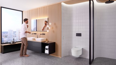 Uomo in bagno davanti allo specchio quadrato Geberit Option Plus e al mobile bagno Geberit ONE nero (© Geberit)