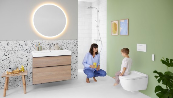 Donna e bambino in un bagno dai colori vivaci con specchio Geberit Option e Geberit AquaClean Alba Donna e bambino in un bagno dai colori vivaci con specchio Geberit Option e Geberit AquaClean Alba