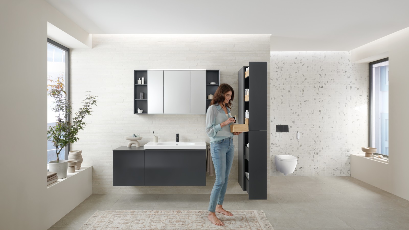 Donna che apre un mobile alto con tanto spazio contenitivo in un bagno con mobili Geberit Acanto