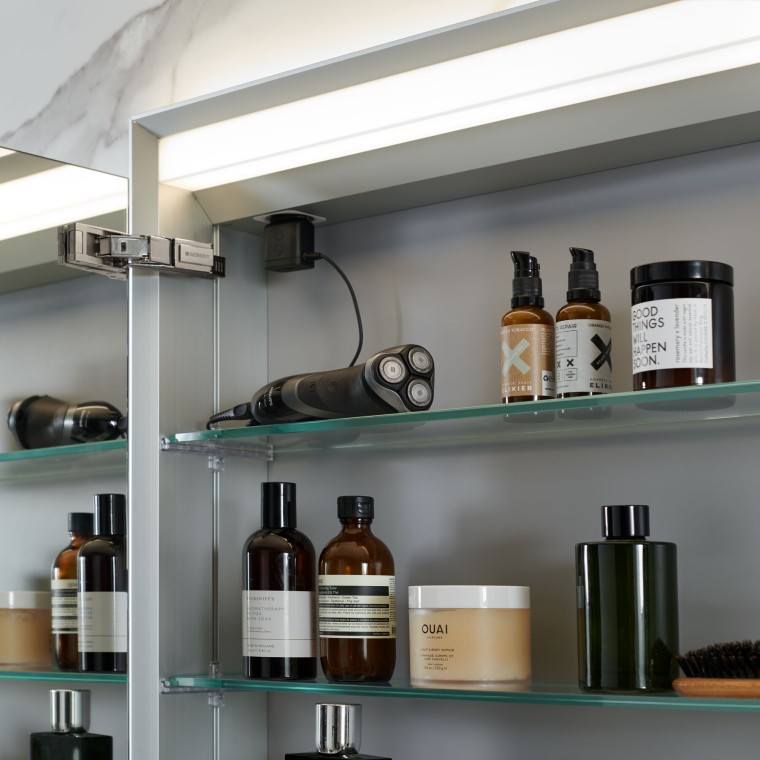 Mobile con specchio contenitore Geberit aperto con prodotti da bagno all’interno Mobile con specchio contenitore Geberit aperto con prodotti da bagno all’interno