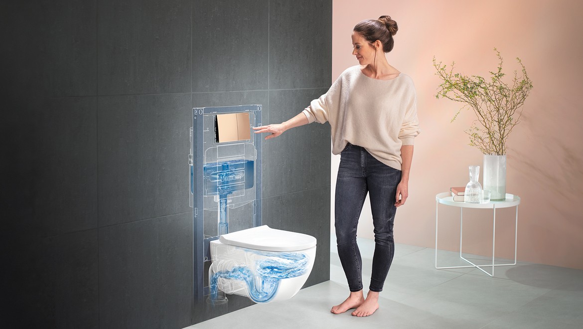 Persona che preme placca di comando Geberit in un bagno con WC Acanto e WC System con TurboFlush Persona che preme placca di comando Geberit in un bagno con WC Acanto e WC System con TurboFlush