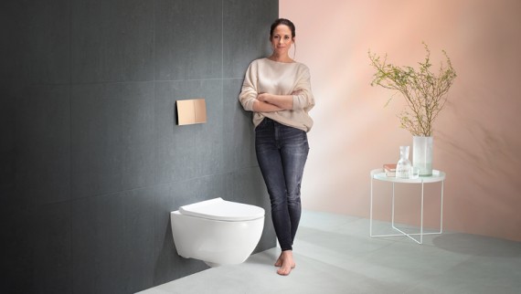 Donna accanto a un WC e ad una placca di comando Geberit