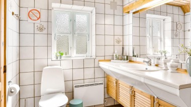 Bagno originale con WC a pavimento, piastrelle bianche e mobili da bagno in legno (© @triner2 e @strandparken3)