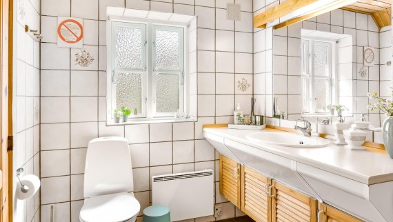 Bagno originale con WC a pavimento, piastrelle bianche e mobili da bagno in legno (© @triner2 e @strandparken3)