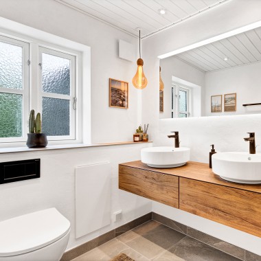 Bagno luminoso e rinnovato con due lavabi rotondi, un grande specchio e mobili da bagno in legno (© @triner2 e @strandparken3)