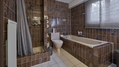 Bagno con piccolo angolo doccia, vasca da bagno e vaso WC a pavimento