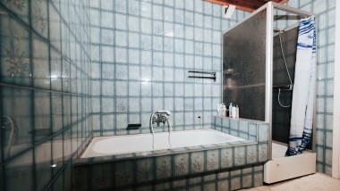 Bagno con piastrelle blu, box doccia e vasca