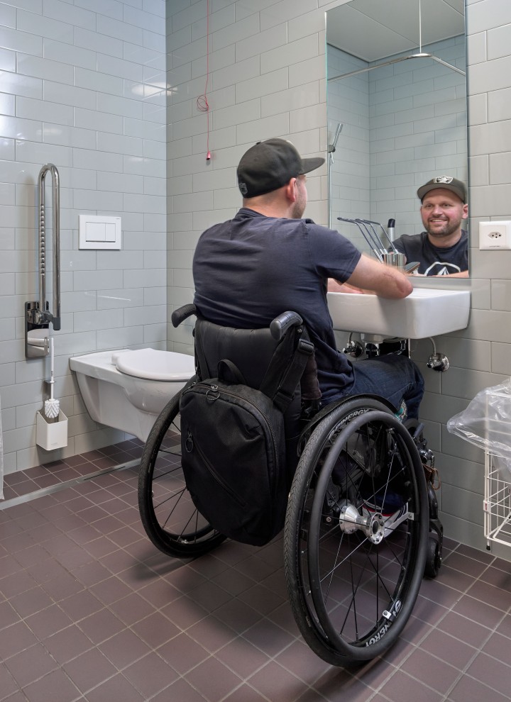 Peter Roos sulla sua sedia rotelle nella zona lavabo di un bagno senza barriere (© Ben Huggler) Peter Roos sulla sua sedia rotelle nella zona lavabo di un bagno senza barriere (© Ben Huggler)