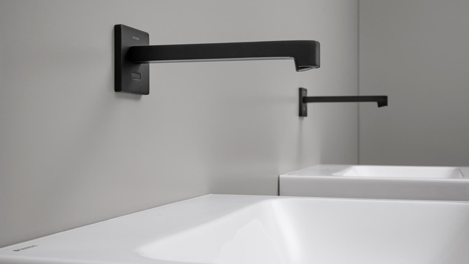 Rubinetto per lavabo senza contatto Geberit Brenta. Rubinetto a parete dal design quadrato in nero opaco. Rubinetto per lavabo senza contatto Geberit Brenta. Rubinetto a parete dal design quadrato in nero opaco.