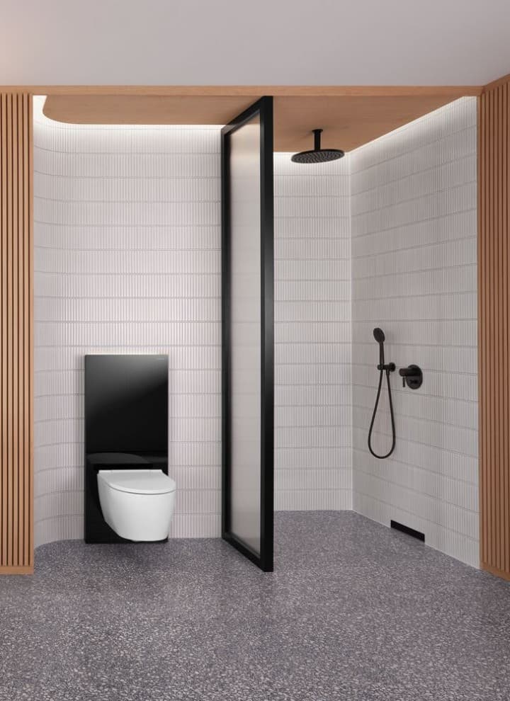 Bagno con parete in legno, con zona doccia e scarico a parete, vaso WC in bianco con Geberit Monolith nero Bagno con parete in legno, con zona doccia e scarico a parete, vaso WC in bianco con Geberit Monolith nero