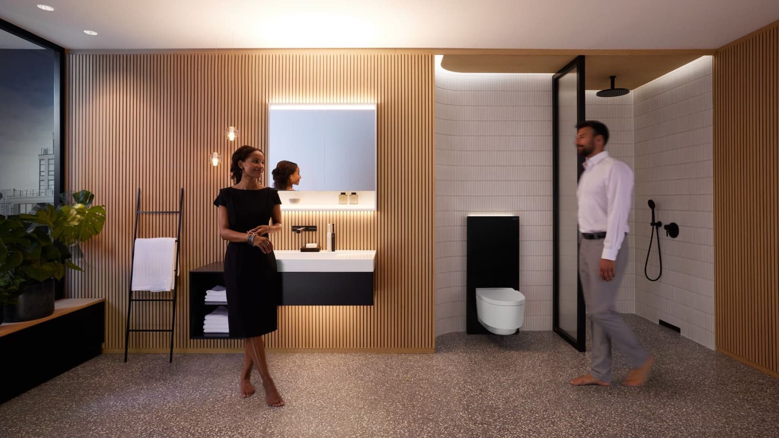Uomo e donna in un bagno perfettamente illuminato con i prodotti Geberit ONE Uomo e donna in un bagno perfettamente illuminato con i prodotti Geberit ONE
