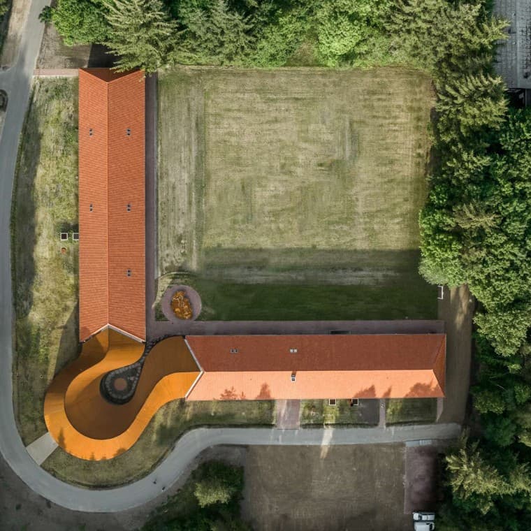 La vista dall'alto mostra il nuovo edificio circolare che collega i due edifici storici con i tetti in tegole (© R_Hjortshoj) La vista dall'alto mostra il nuovo edificio circolare che collega i due edifici storici con i tetti in tegole (© R_Hjortshoj)